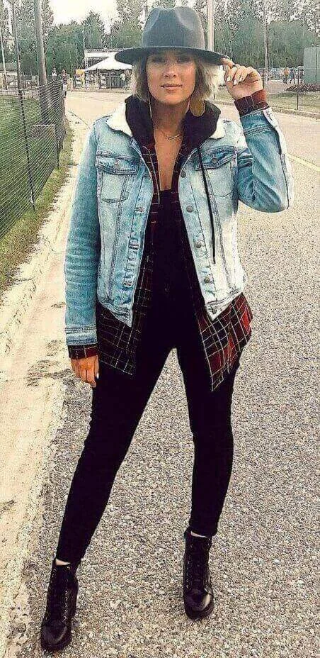 Girl wearing a black top with black tights a flannel print shirt and a denim jacket