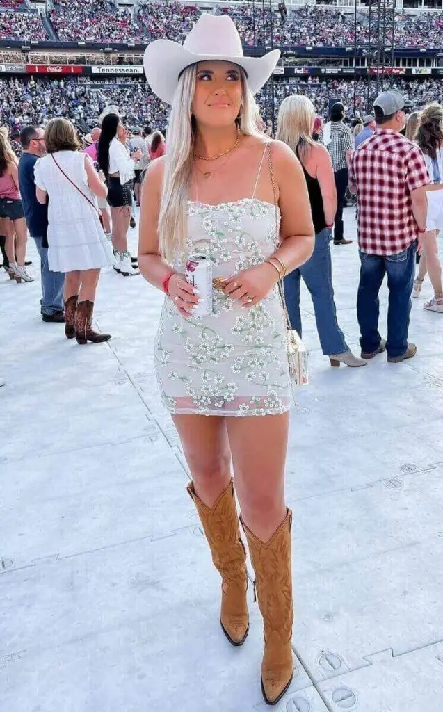 Girl wearing a white floral dreass with a white hat at a country concert