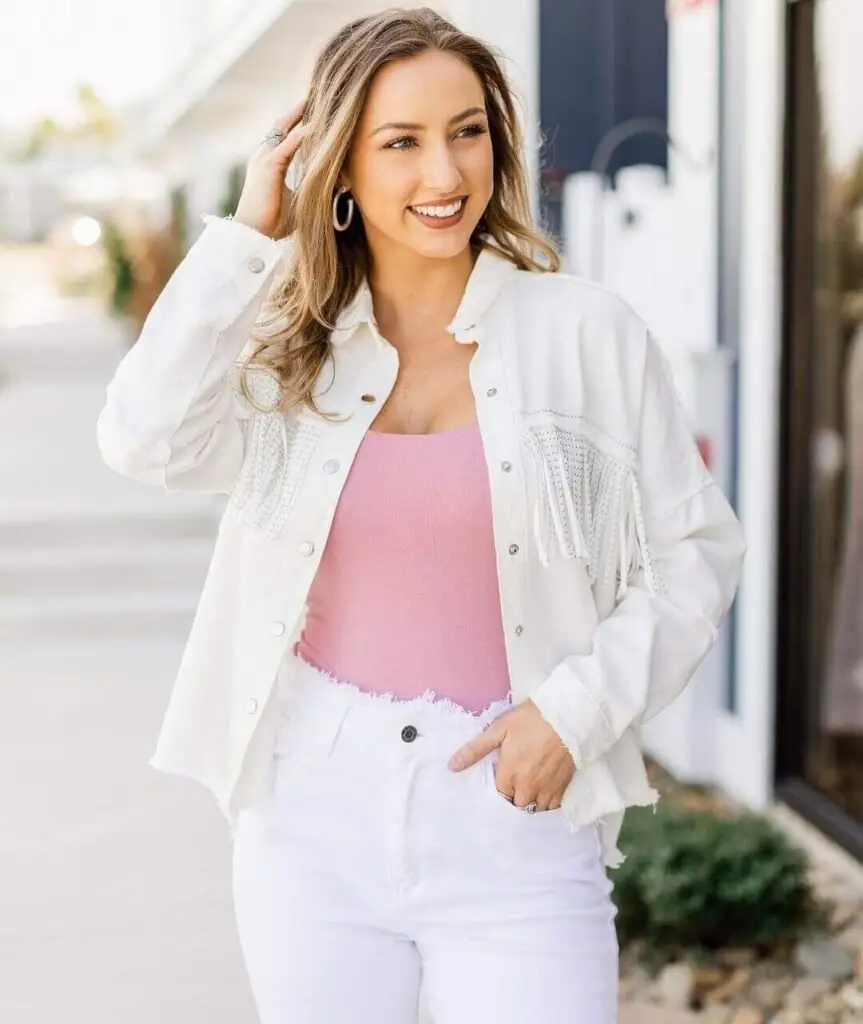 Girl wearing a white fringe jacket with white pants and pastel pin top underneath