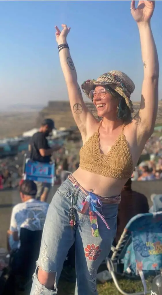Girl wearing a crochet bikini top with ripped jeans and a hat at a dave matthews band concert