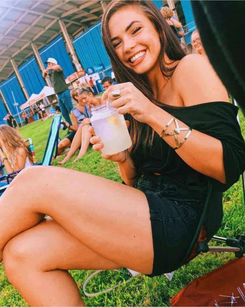 Girl wearing an off shoulder black top with black jean shorts at a dave matthews band concert